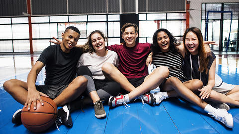 Teens sit on basketball court together
