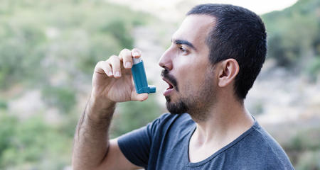 Man using his inhaler outside.