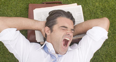 Man yawning with a briefcase on the grass