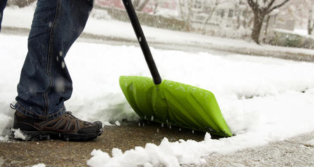 Person Shoveling Snow with a Green Shovel
