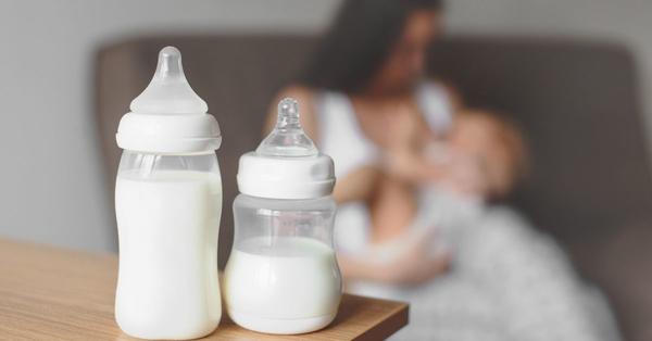 Baby bottles full of formula and woman breastfeeding in background